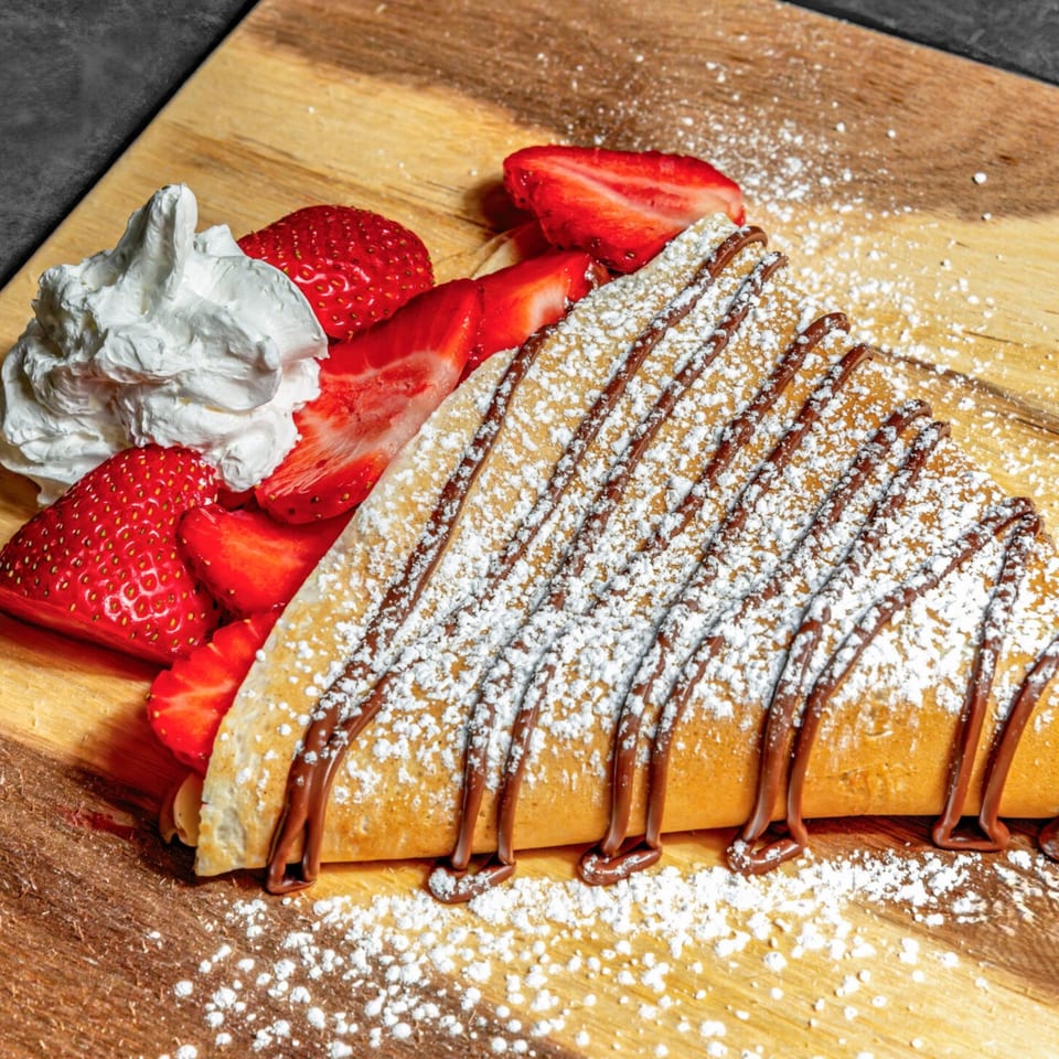 Chunky Bites' strawberry and chocolate crepe, dusted with powdered sugar and served with whipped cream.